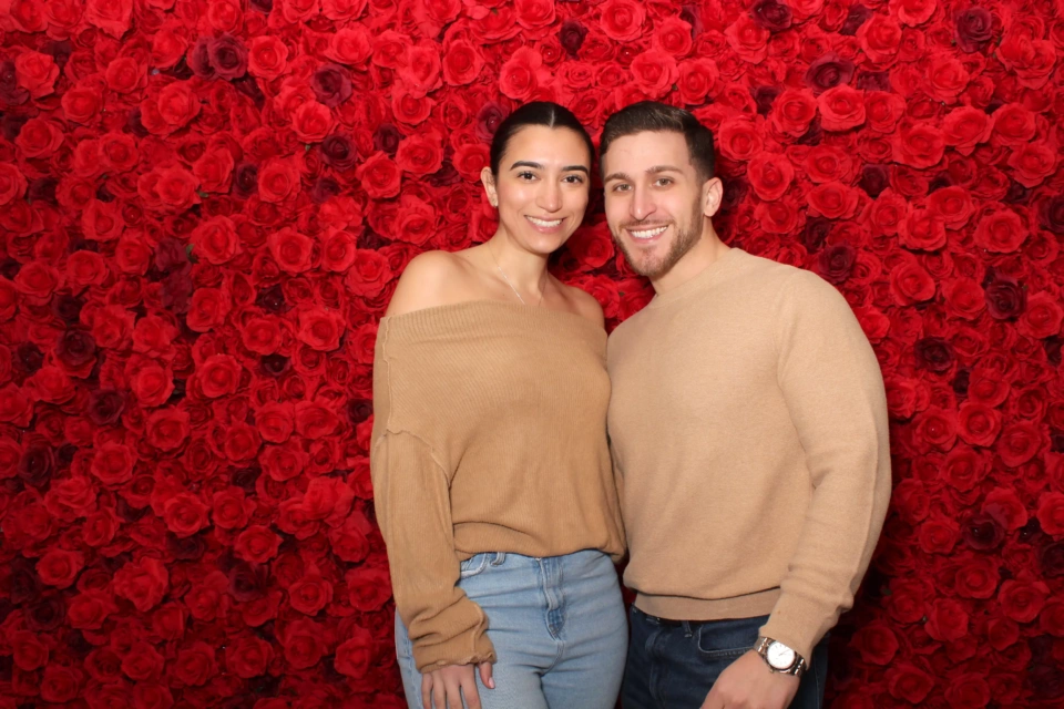 Red flower wall photo booth rental NYC — vibrant floral backdrop for weddings and events