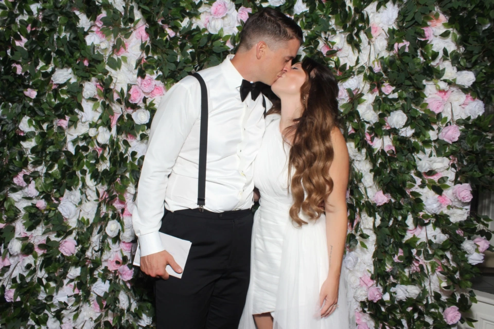 Green flower wall photo booth rental NYC — guests posing at wedding reception