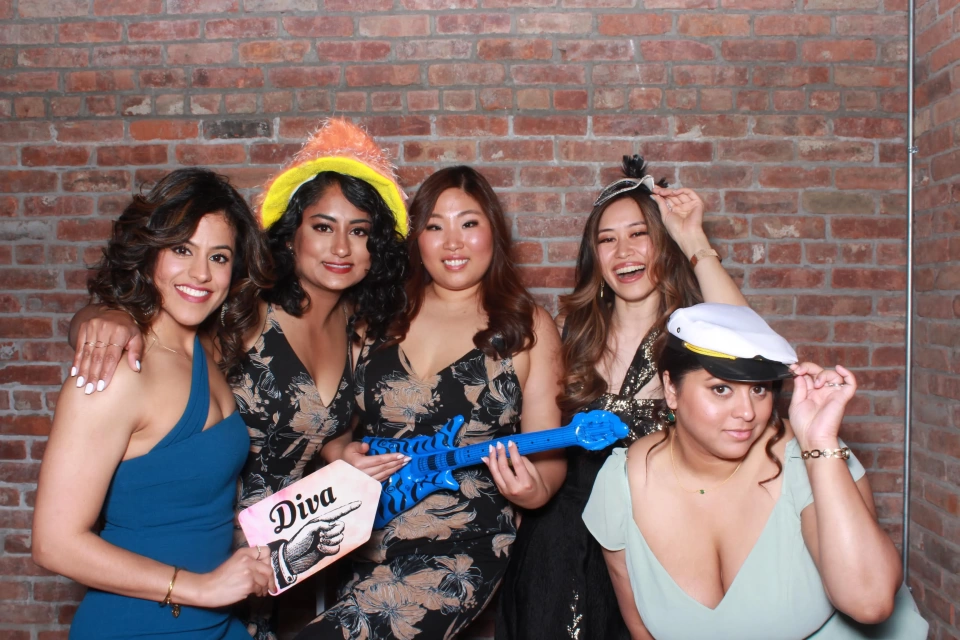 Wedding photo booth rental NYC — guests posing with gold sequin backdrop and props